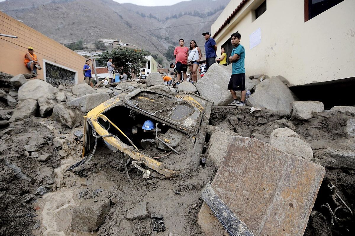 Calle de Chosica cubierta de lodo y rocas, con un auto aplastado, tras el huaico de 2015